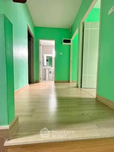 Spacious hallway with vibrant green walls and light wood flooring