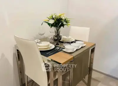 Modern dining area with elegant table setting and floral centerpiece in a cozy apartment.