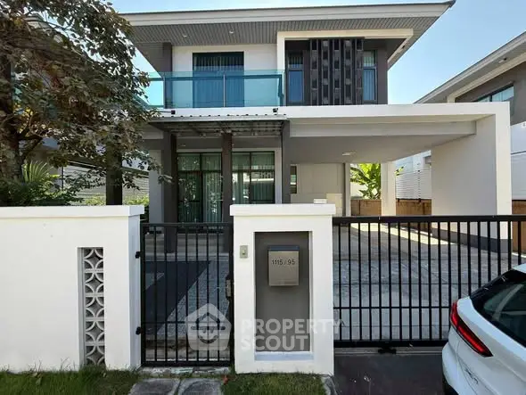Modern two-story house with sleek design and gated entrance in a suburban neighborhood.