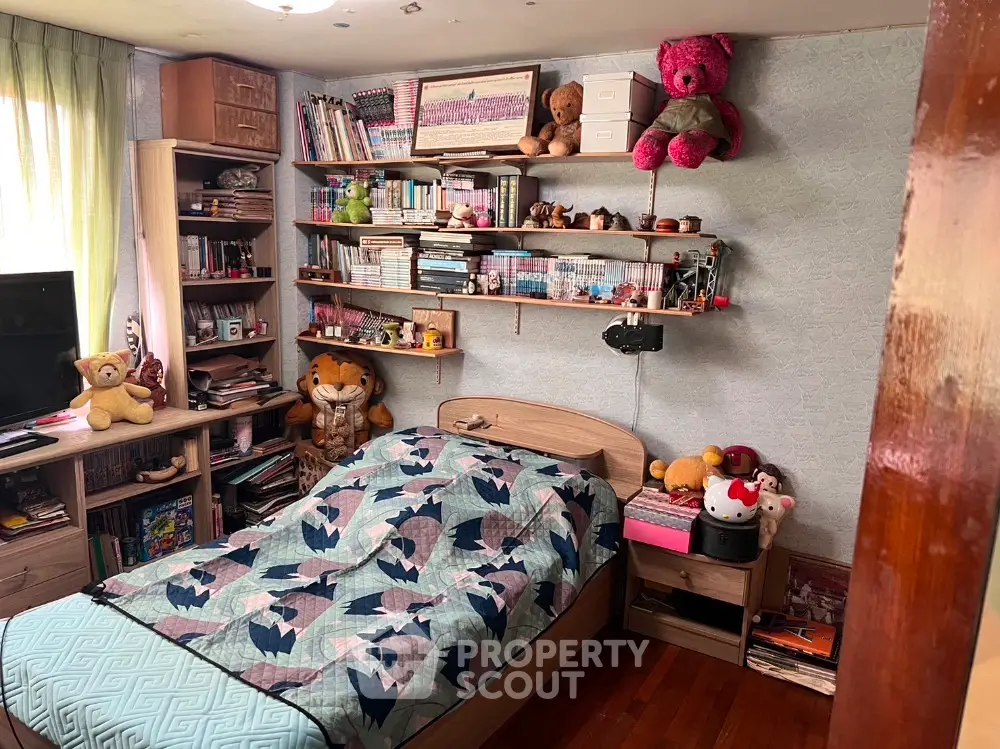 Cozy bedroom filled with personal touches, featuring a comfortable bed, ample shelving with books and collectibles, and warm lighting.