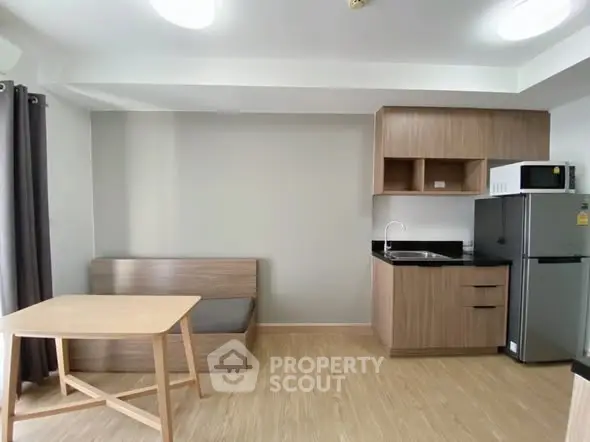 Modern compact kitchen with wooden cabinetry and dining area in apartment