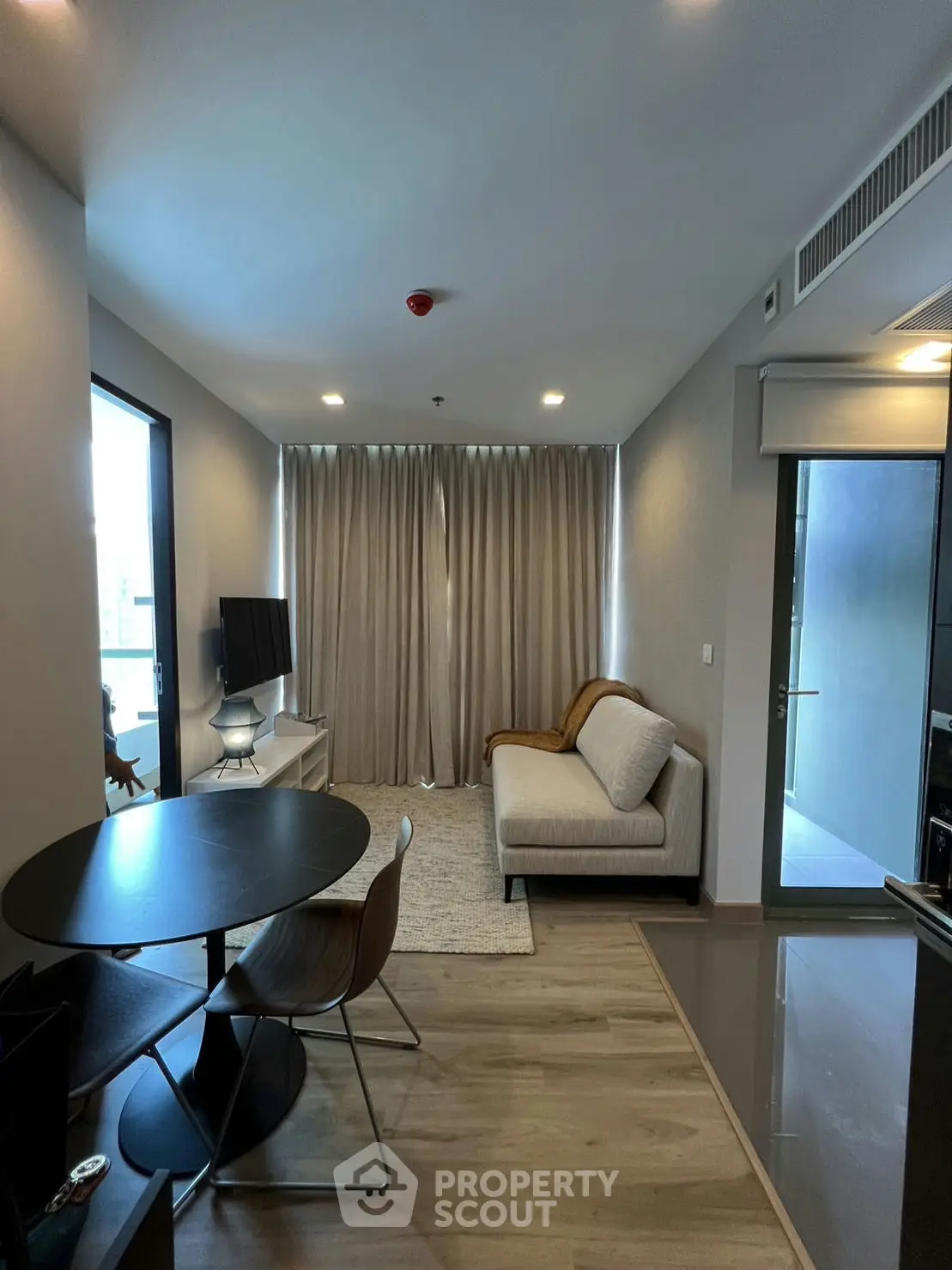 Modern living room with cozy sofa, TV, and dining area in a stylish apartment.