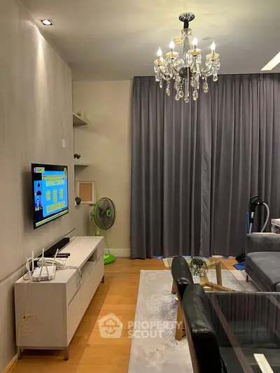 Elegant living room with chandelier, modern TV setup, and cozy seating area.