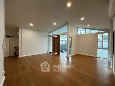 Spacious open-plan living room with high ceilings and wooden flooring