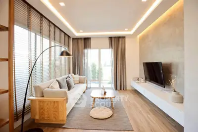 Modern living room with stylish decor, large windows, and cozy seating area.