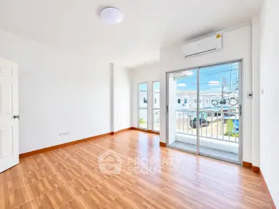 Spacious bright room with wooden flooring and balcony access in modern apartment.