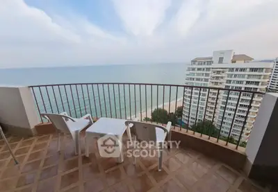 Stunning ocean view from spacious balcony with seating area in high-rise apartment.