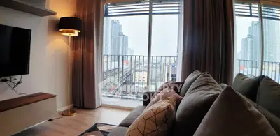 Modern living room with cozy sofa and city view from balcony, perfect for urban living.