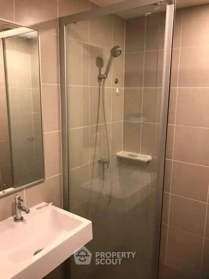 Modern bathroom with glass shower enclosure and sleek sink design.