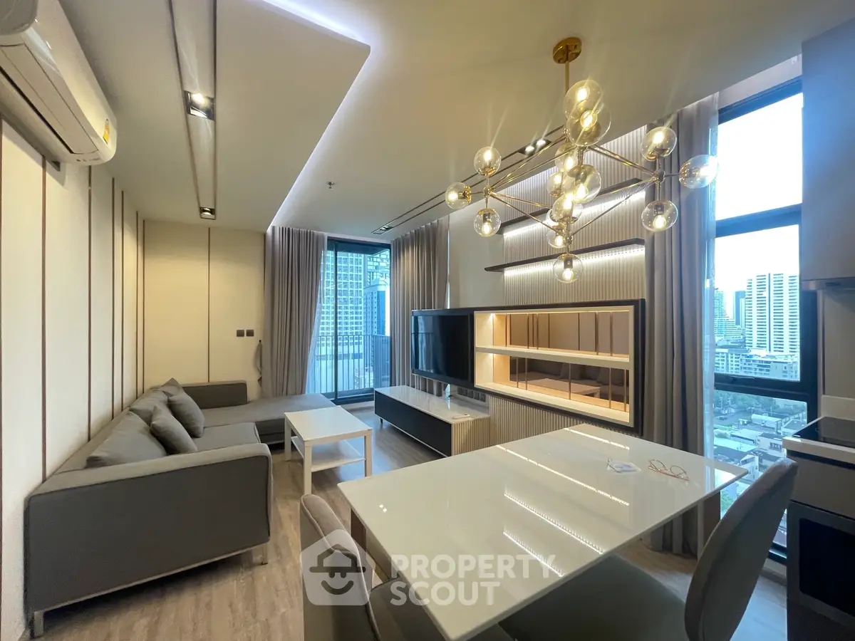 Modern living room with stylish lighting and city view, featuring sleek furniture and floor-to-ceiling windows.
