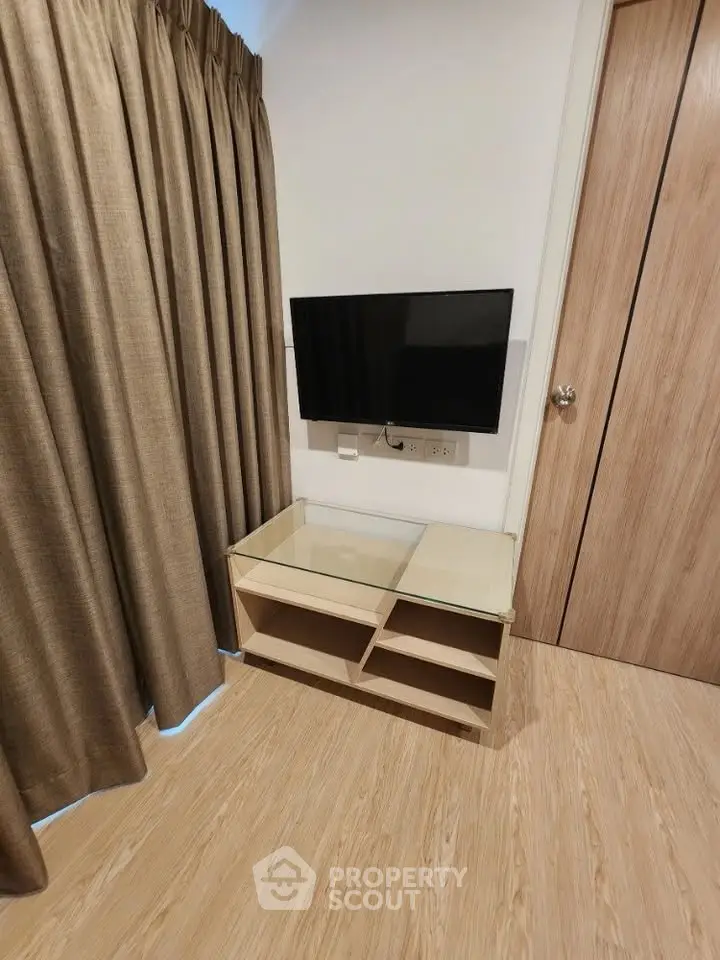 Modern living room corner with wall-mounted TV and stylish glass table