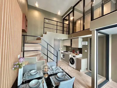 Modern duplex apartment with stylish interior, featuring open kitchen and dining area, and elegant staircase.