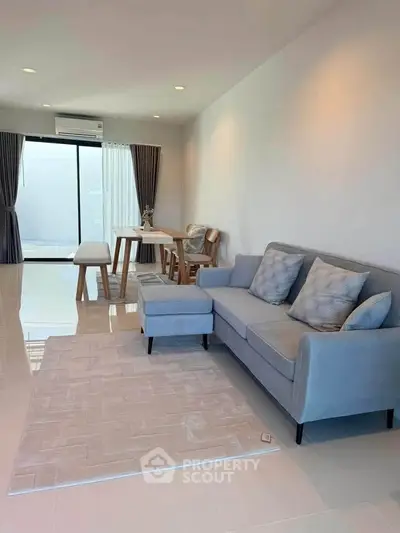Modern living room with stylish sofa and dining area, featuring elegant decor and natural light.