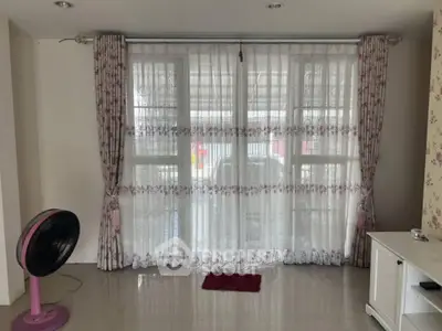 Spacious living room with large windows and elegant curtains