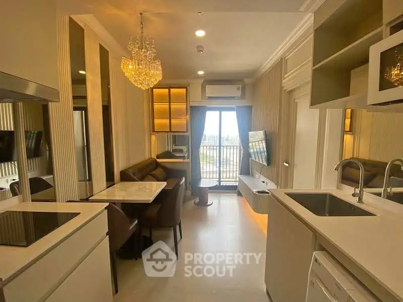 Modern open-layout kitchen and living area with chandelier and balcony view
