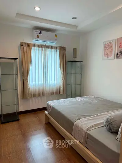 Cozy bedroom with modern decor and natural light, featuring a comfortable bed and elegant glass cabinets.
