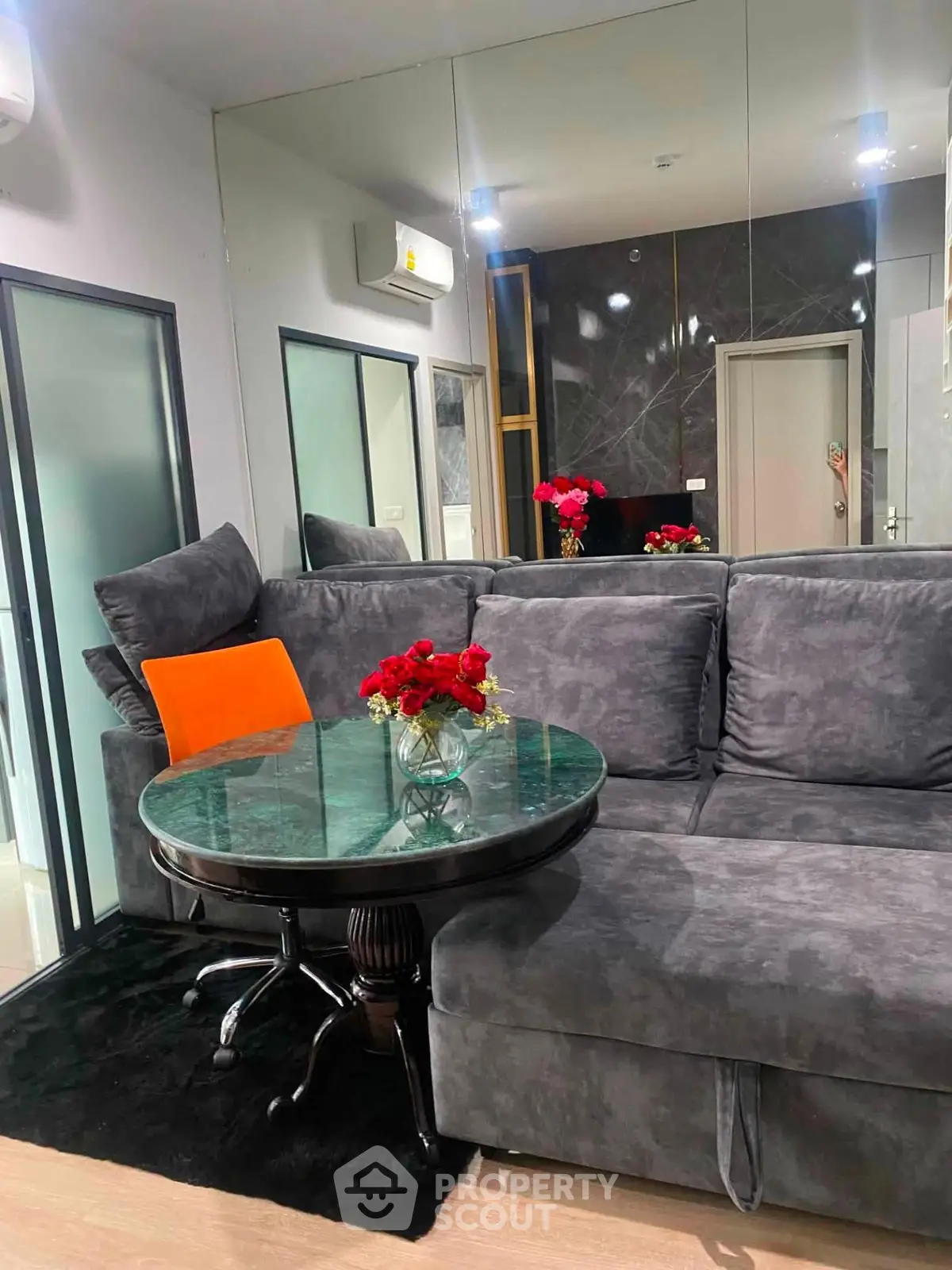 Modern living room with plush gray sofa, glass table, and elegant decor accents.
