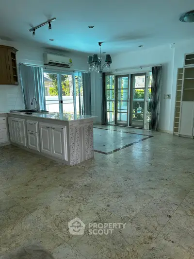 Spacious open-layout kitchen with marble flooring and large windows for natural light.