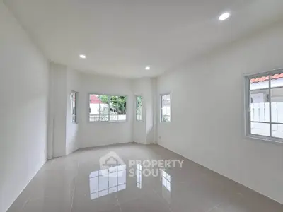 Spacious unfurnished room with large windows and glossy tiled floor, perfect for customization.