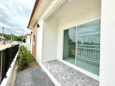 Modern home exterior with sliding glass doors and tiled patio, perfect for outdoor relaxation.