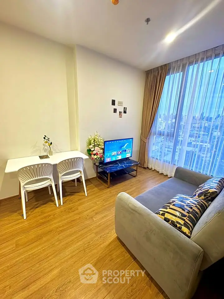 Modern living room with cozy sofa, TV, and dining area in bright apartment