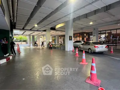 Modern building entrance with parking area and traffic cones, showcasing urban convenience and accessibility.