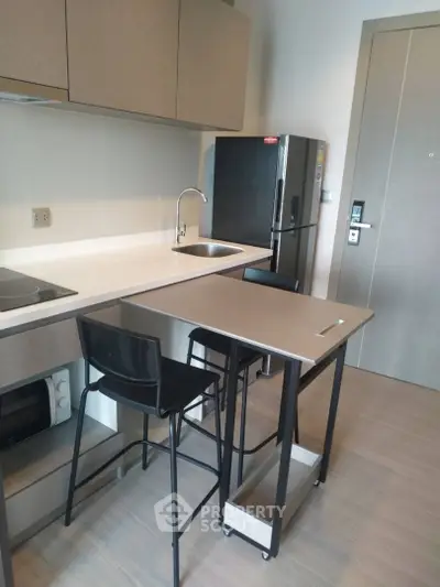 Modern kitchen with sleek design, featuring compact dining area and stainless steel appliances.