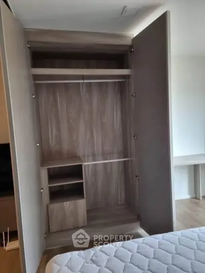Spacious wooden wardrobe in modern bedroom with open doors showcasing ample storage space.