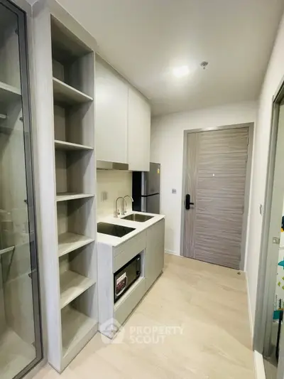 Modern compact kitchen with sleek cabinetry and built-in appliances in a stylish apartment.