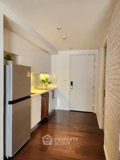 Modern kitchen with stainless steel appliances, sleek cabinetry, and warm wooden flooring complemented by chic brickwork walls.