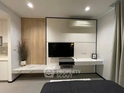 Modern bedroom with sleek TV setup and air conditioning, featuring stylish decor and neutral tones.