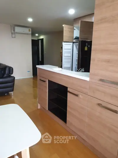 Modern open-plan kitchen with wooden cabinetry and sleek appliances in a stylish apartment.