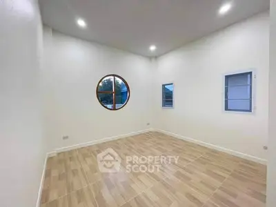 Spacious room with unique round window and modern lighting
