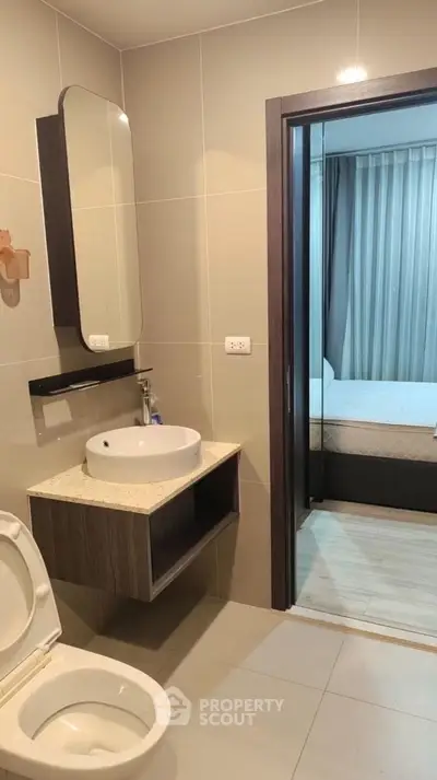 Modern bathroom with sleek fixtures and view into cozy bedroom