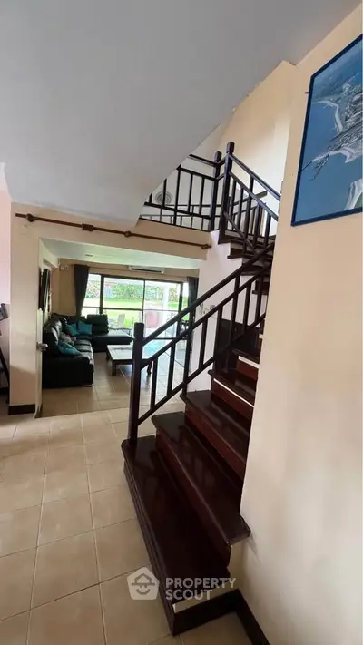 Spacious living room with elegant staircase and large windows offering garden views.