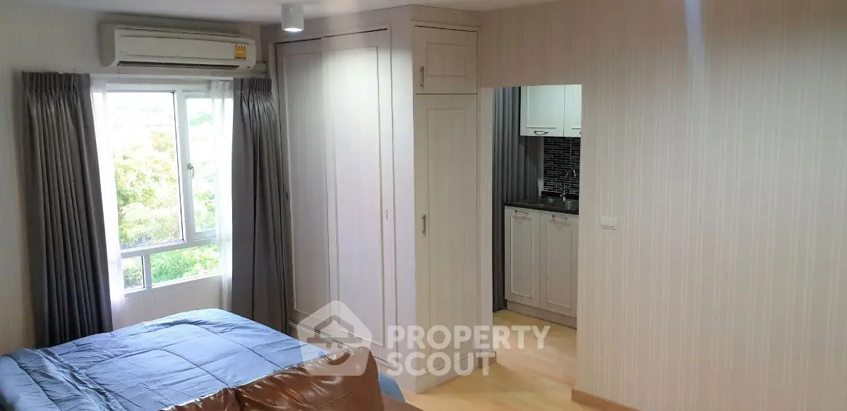 Cozy bedroom with built-in wardrobe and partial kitchen view in modern apartment
