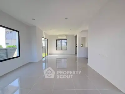 Spacious modern living room with large windows and glossy tiled floors