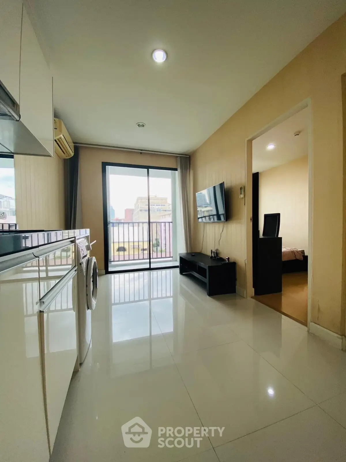 Modern apartment with sleek kitchen and living area, featuring large windows and a view of the cityscape.