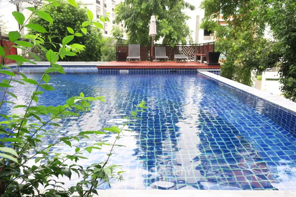 Luxurious outdoor pool with lush greenery and sun loungers, perfect for relaxation and leisure.