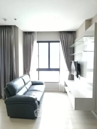 Modern living room with sleek sofa and wall-mounted TV in bright apartment