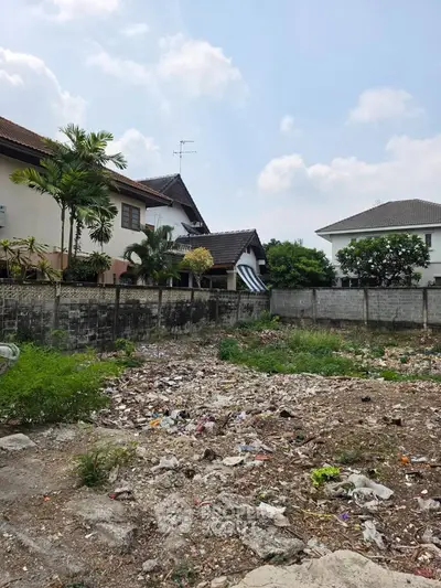 Vacant land plot in residential area with potential for development, surrounded by houses and greenery.
