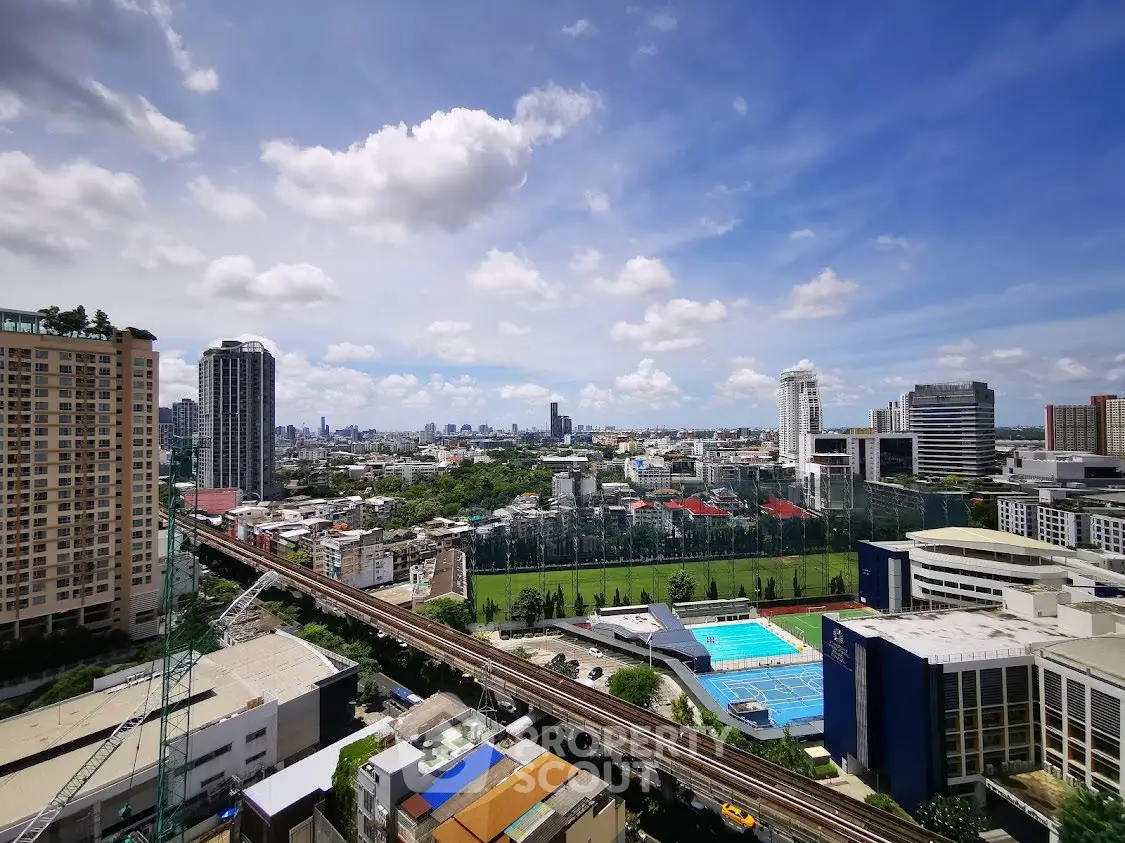 Stunning cityscape view with modern buildings and lush greenery under a vibrant blue sky.