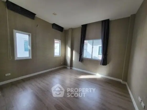 Spacious empty room with large windows and wooden flooring, perfect for customization.