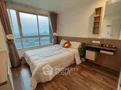 Cozy bedroom with large window offering stunning city views, featuring wooden flooring and modern decor.