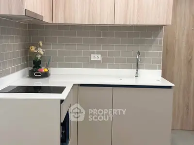 Modern kitchen with sleek cabinetry and stylish backsplash, featuring an electric cooktop and minimalist design.