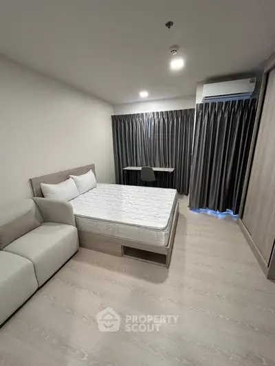 Modern bedroom with minimalist design, featuring a cozy bed, sofa, and study desk, ideal for urban living.