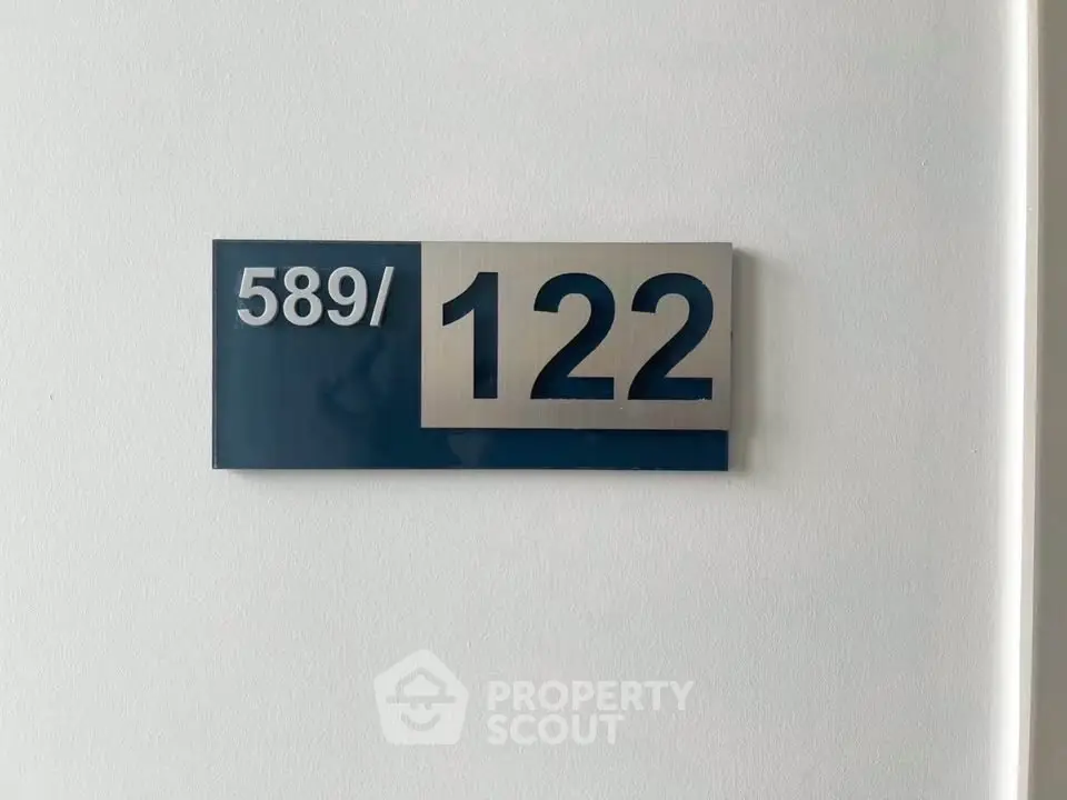 Modern apartment number sign on a white wall, sleek and stylish design.