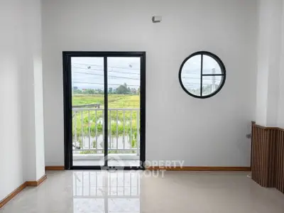 Bright room with large window and balcony overlooking green fields