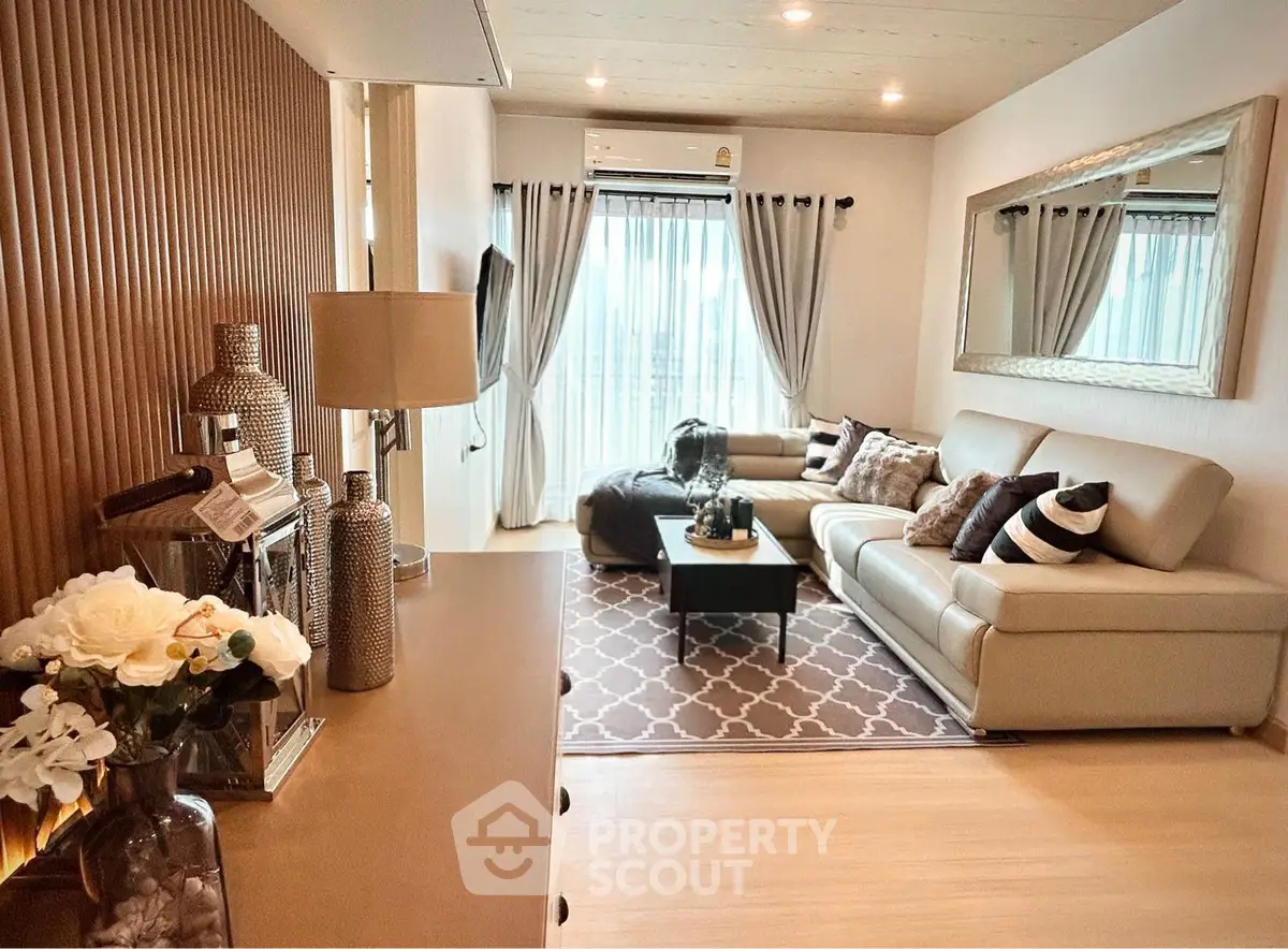 Elegant living room with modern decor, cozy seating, and large mirror enhancing space.