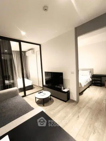 Modern living room with sleek furniture and open layout, leading to a cozy bedroom.